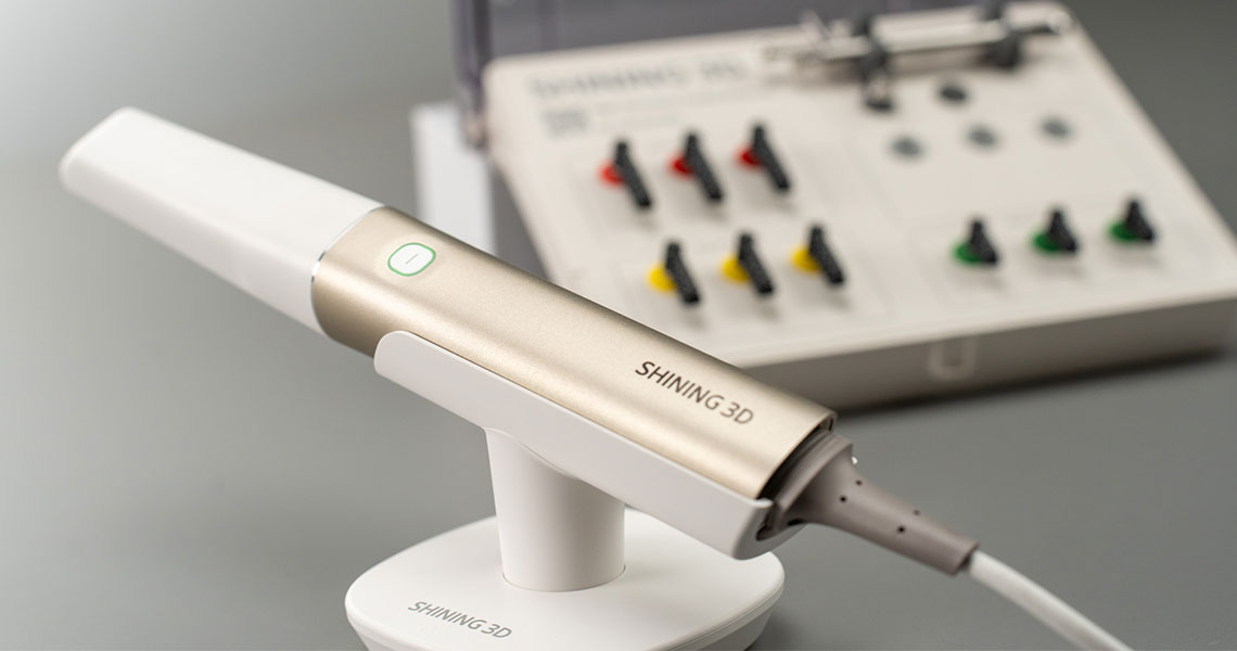 Aoralscan Elite von Shining 3D: Das sagen Experten Der Intraoralscanner Aoralscan Elite auf einer Halterung und mit einem Scanbody-Kit im Hintergrund